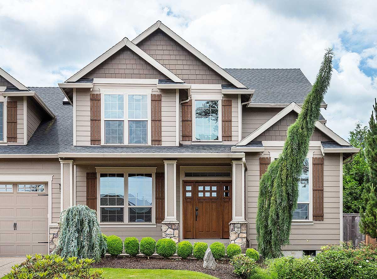 Craftsman house plan exterior with a covered porch, gabled dormers, double-hung windows, and stone-accented columns.