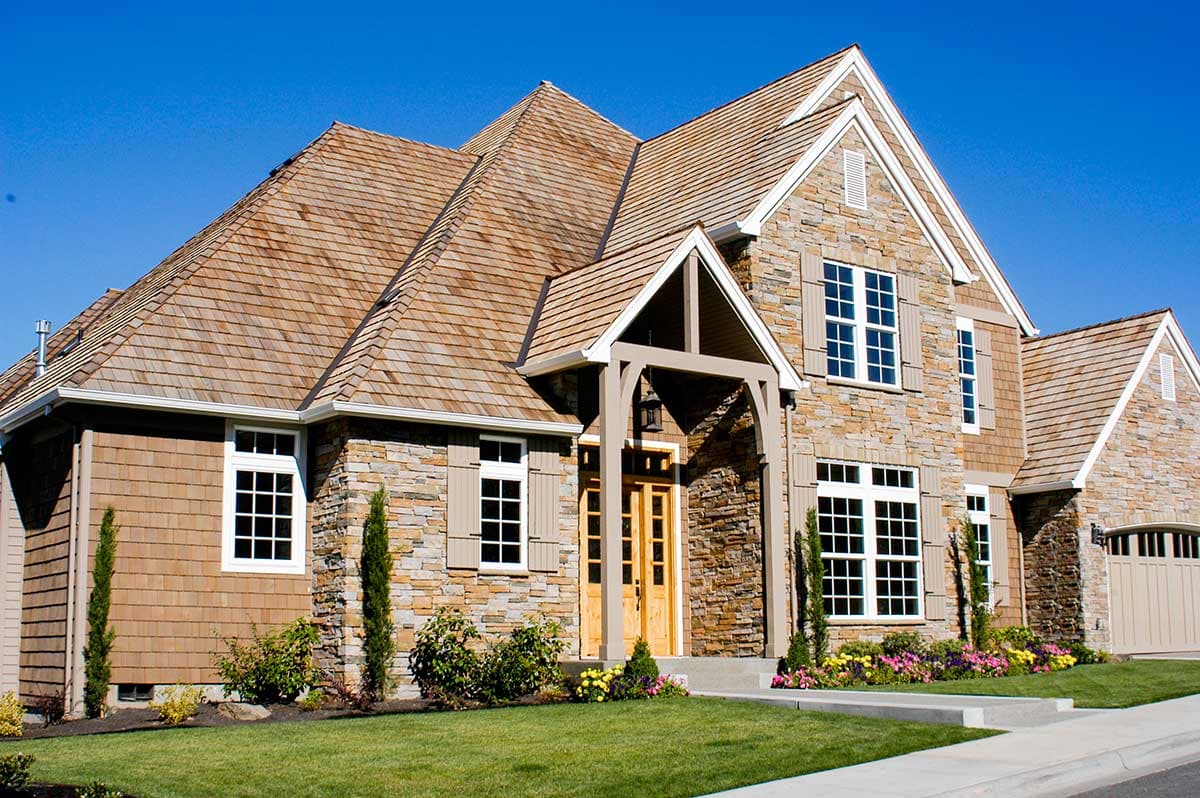 House plan exterior with stone and wood siding, multiple gables, and covered entry with wooden beams.