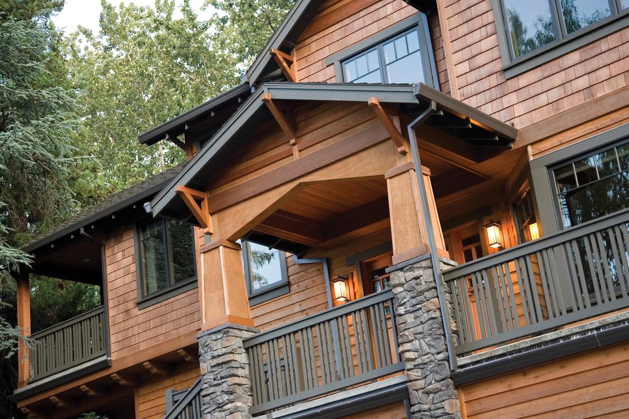 Craftsman style house plan exterior with cedar shake siding, stone-clad columns, covered porch with exposed rafter tails.