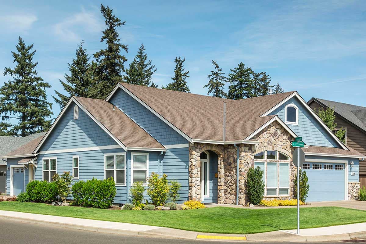 House plan exterior: Ranch style, one story, blue siding, stone-accented entryway, gabled dormer, and attached garage.