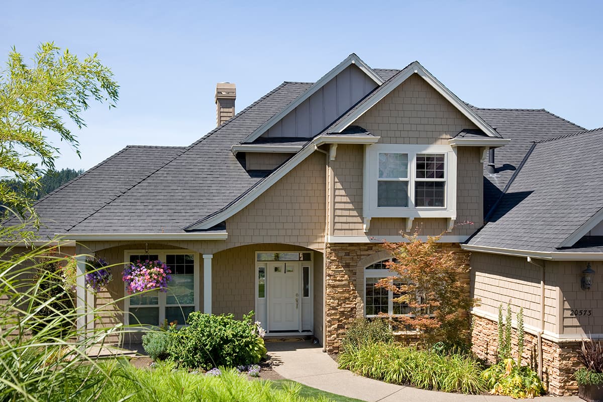 House plan exterior: Two-story home with arched entry, gable details, stone accents, and multiple rooflines.