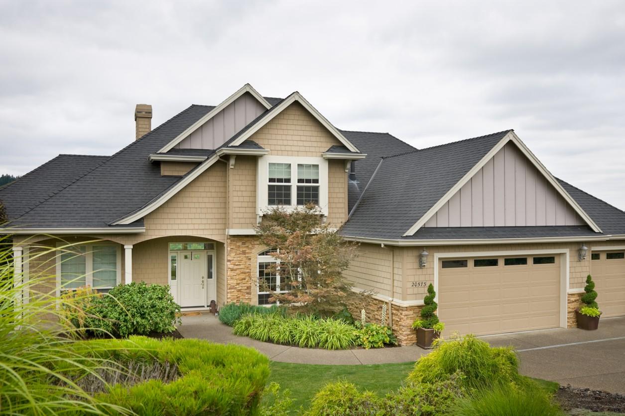 House plan exterior: Two-story home with shingle siding, stone accents, arched entryway, and a three-car garage.