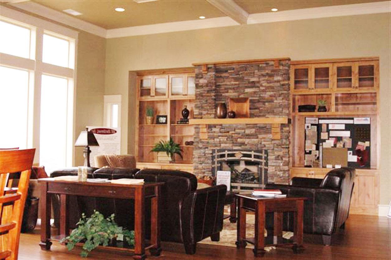 Living room with stone fireplace, built-in wood shelving, and large windows.