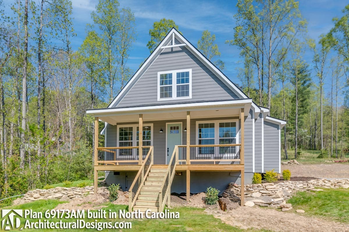 House plan exterior featuring a gable roof, front porch, and vertical siding. The two-story home has a set of stairs leading to the porch.