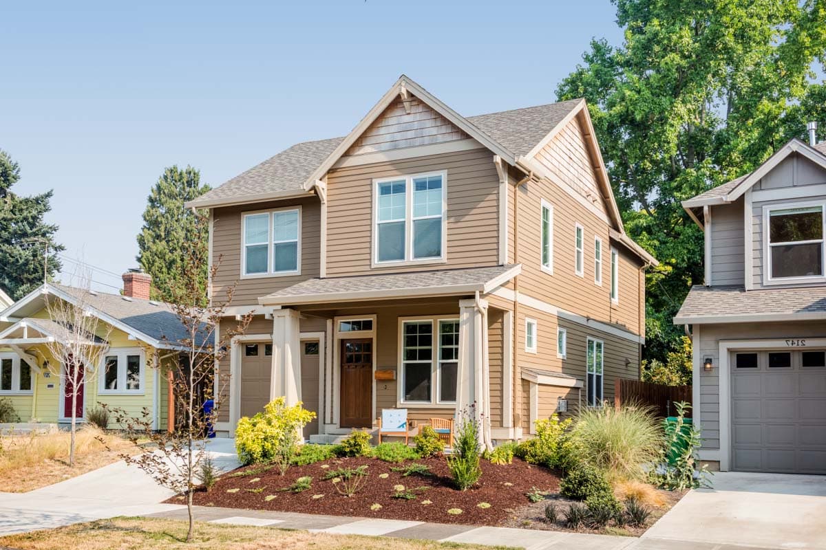 House plan exterior featuring a two-story Craftsman home with a gabled roof, a front porch with columns, and a garage.