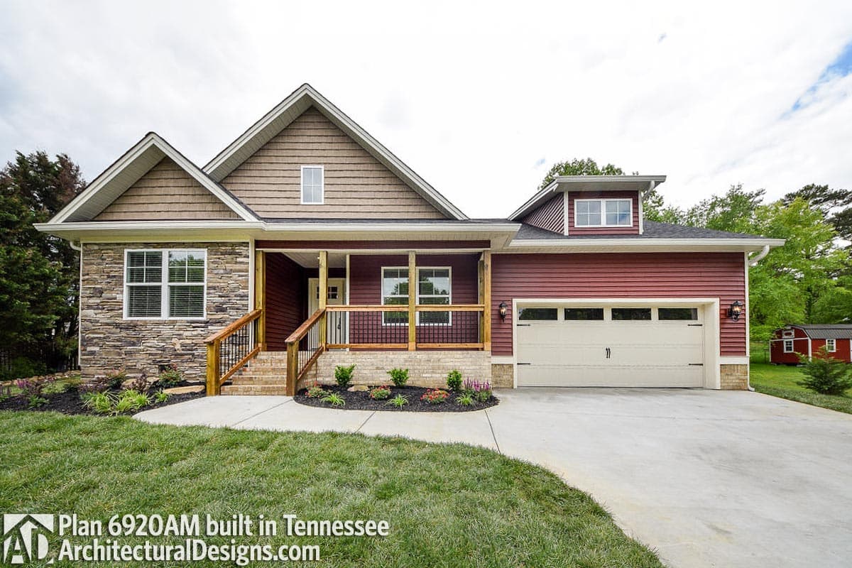 House plan exterior featuring stone and clapboard siding, covered porch with wood railings, and a two-car garage.