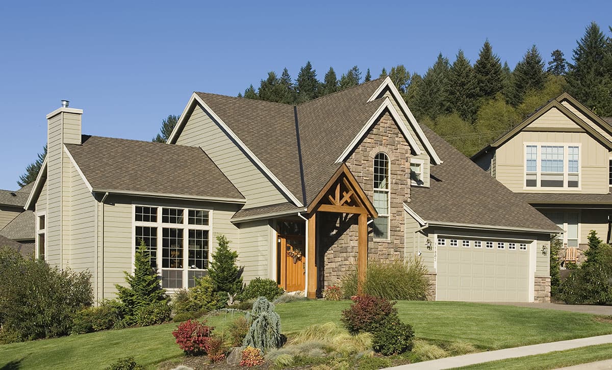 House plan exterior: Two-story home with stone accents, covered entry, prominent chimney, and attached two-car garage.