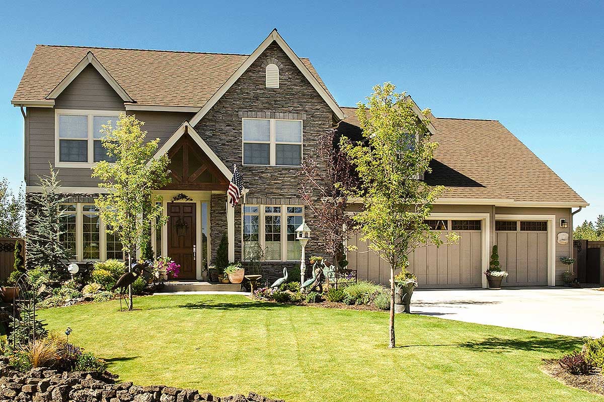 Two-story house plan exterior with stone and siding, prominent gables, covered entry, and a three-car garage.
