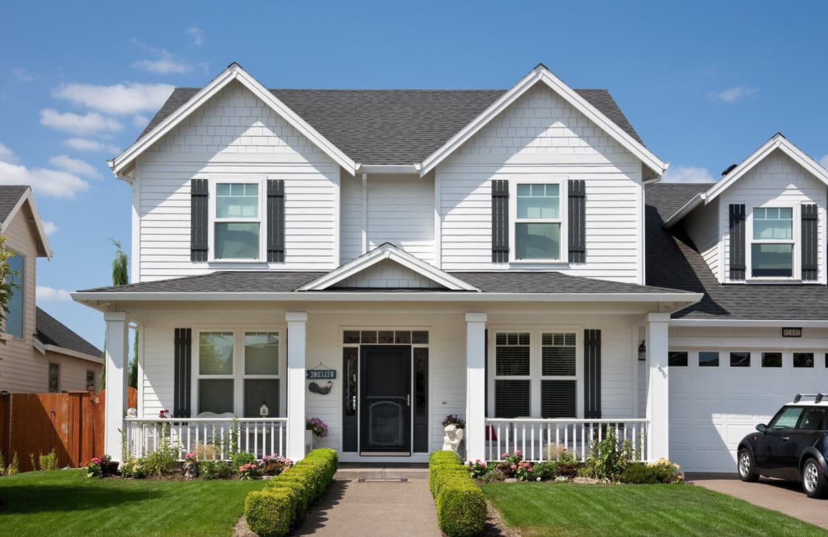 Two-story house plan exterior with a covered front porch, multiple gables, dormer windows, and attached garage.
