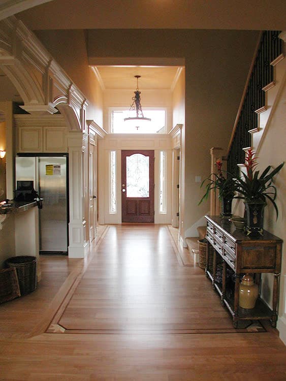 Interior view of a grand entryway with a double-door entrance, transom window, chandelier, and staircase.