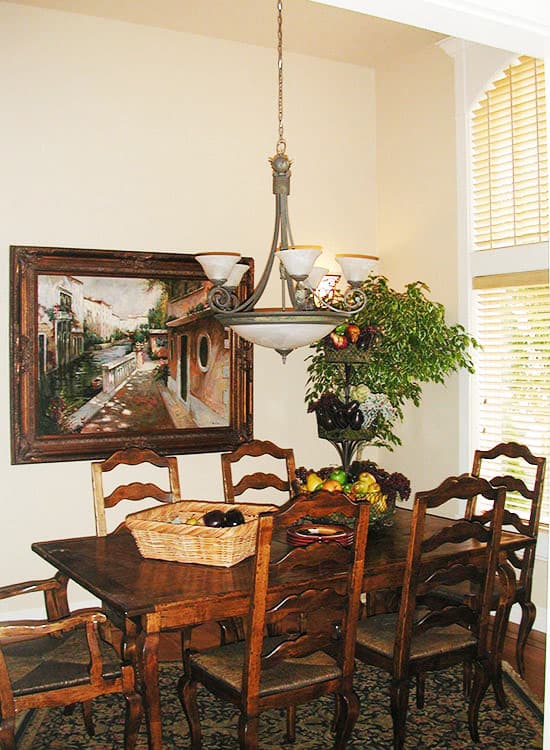 Dining room with wooden table and chairs, artwork, plant, and chandelier.
