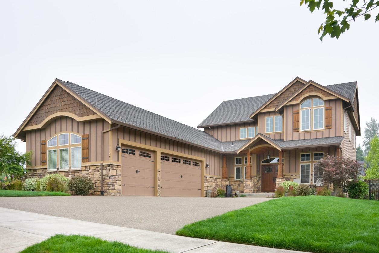 Craftsman style house plan exterior with a three-car garage, stone accents, and arched windows.