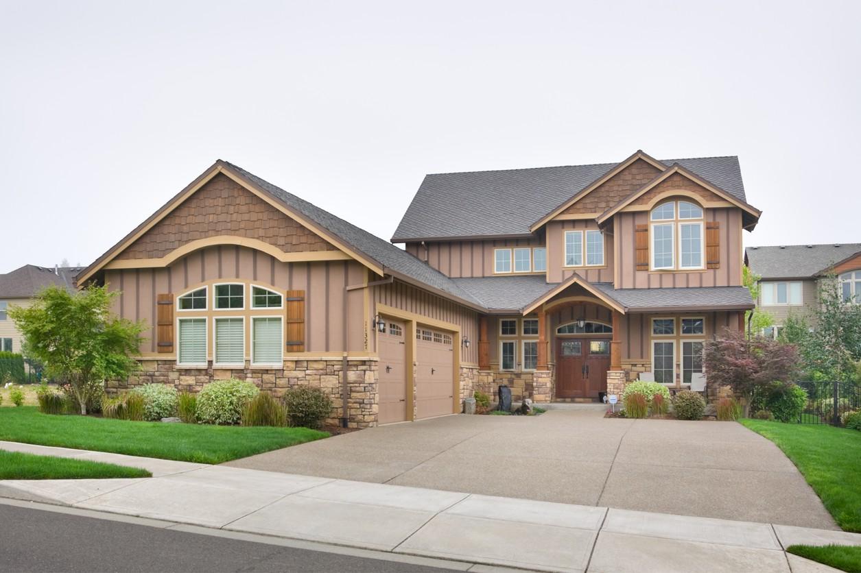 Craftsman style house plan exterior. Two stories with a three-car garage, stone accents, gables, and a covered entry porch.