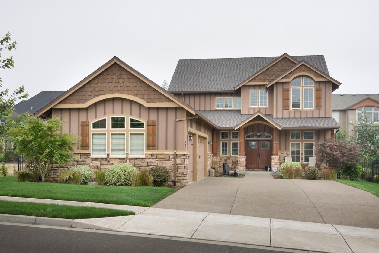 House plan exterior: Two-story home with stone base, gabled dormers, arched windows, and attached garage.