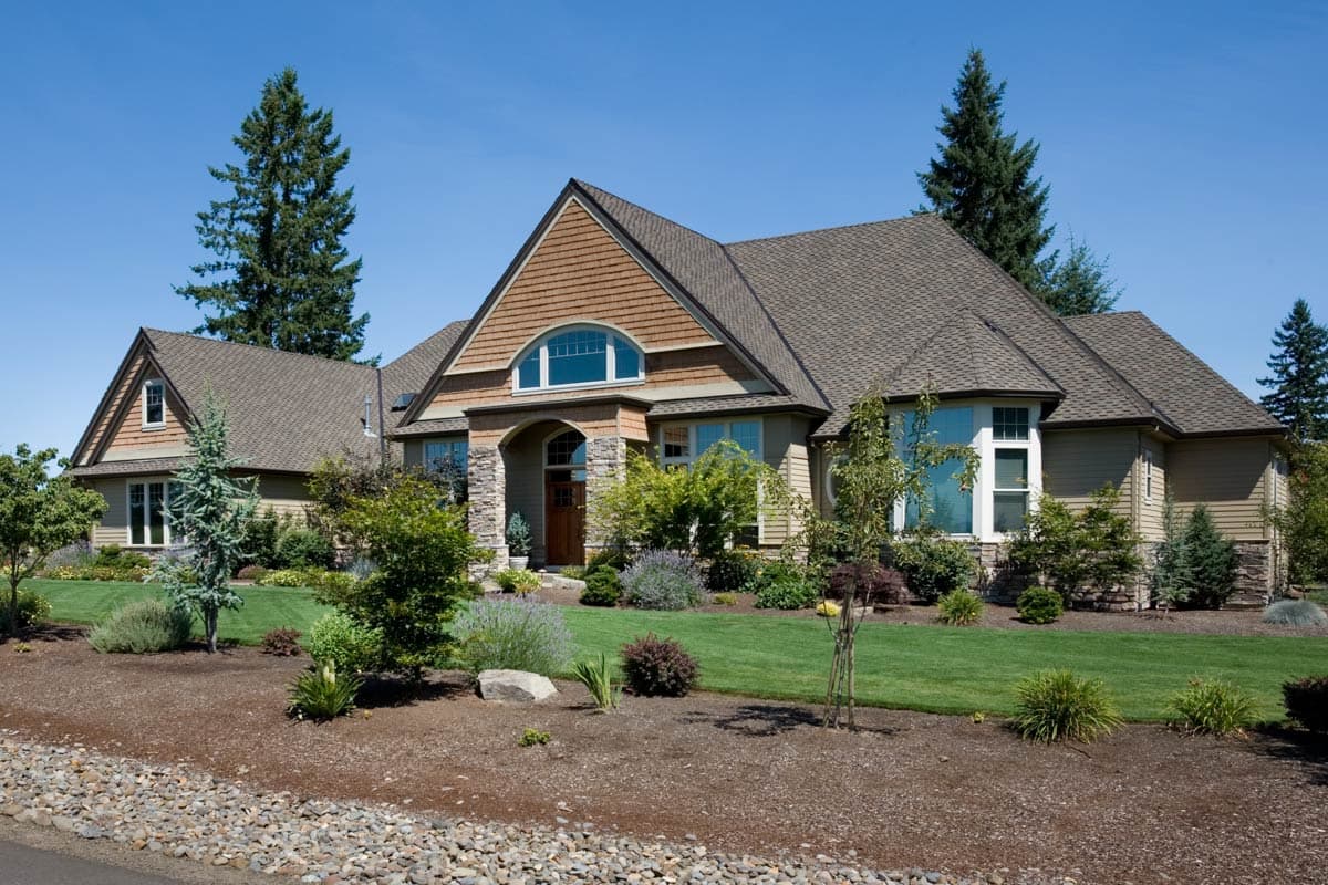 House plan exterior: Single-story home with stone accents, wood siding, prominent gables, and arched window above entry.
