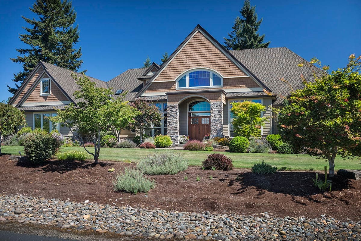 Craftsman-style house plan exterior with arched entry, stone accents, wood door, shingled gables, and multi-story rooflines.