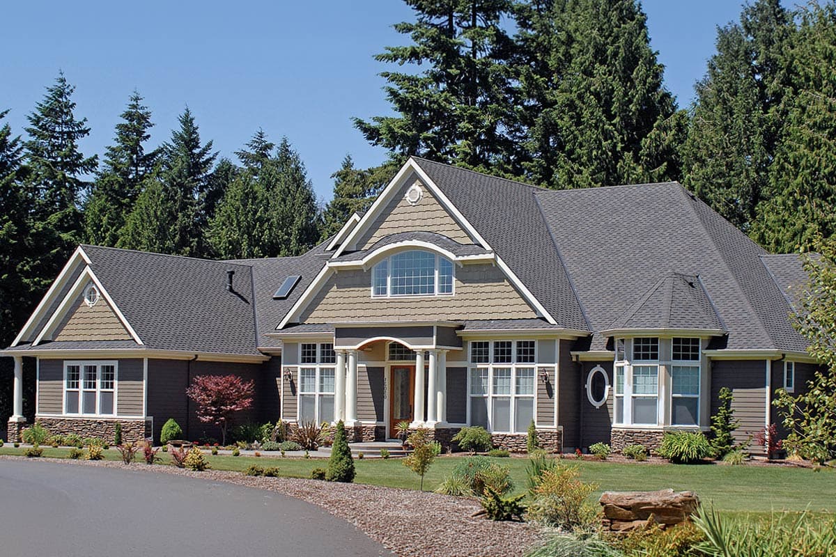 House plan exterior featuring a gable roof, arched dormer window, second-story balcony, and wood entry door with columns.