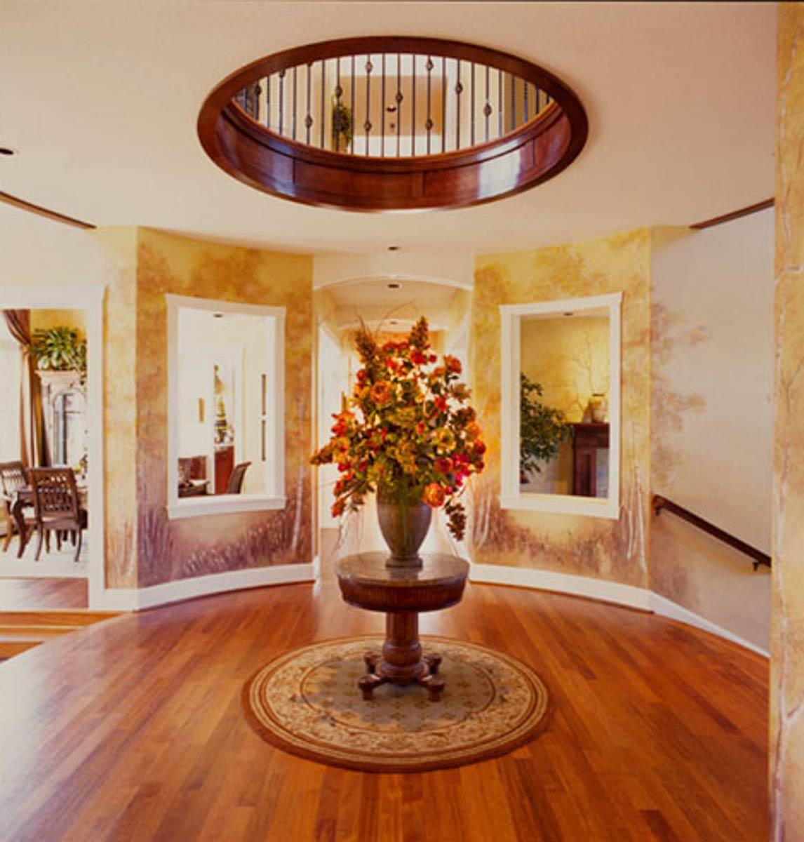 Interior view of a circular foyer with hardwood floors, oval skylight, and decorative wall finishes.