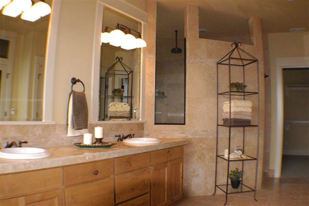 Bathroom vanity with double sinks, wood cabinetry, and walk-in shower with glass enclosure.