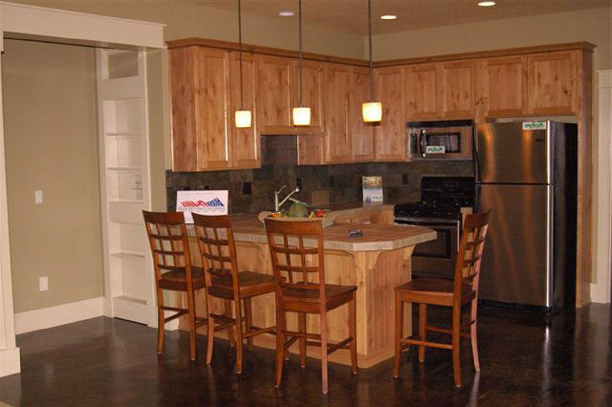 Kitchen with wood cabinets, island seating for four, stainless steel appliances, and a dark floor.