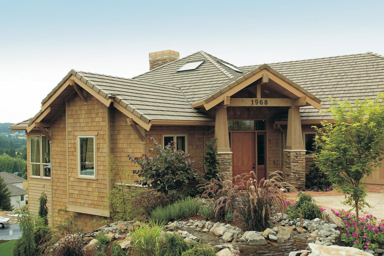 House plan exterior: Wood shake siding, prominent gables with exposed rafter tails, stone base, and covered entry with wooden columns.