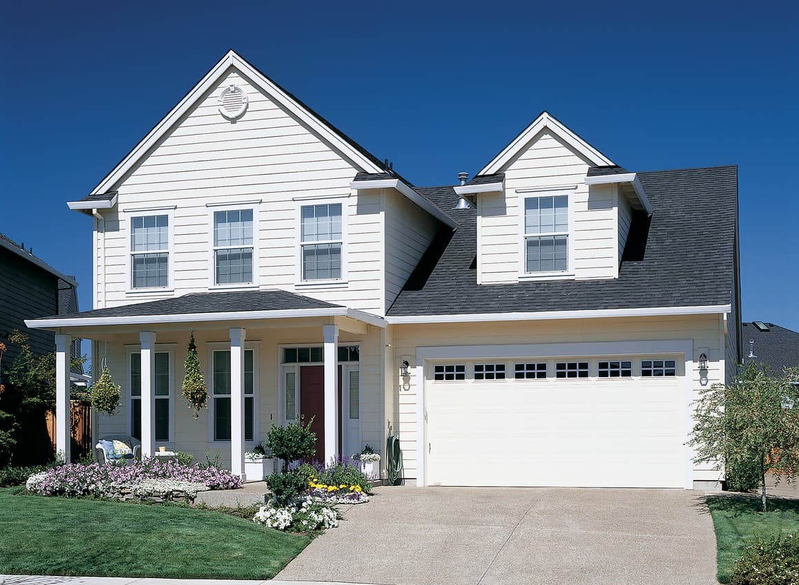 House plan exterior: Two-story home with a covered front porch supported by columns, gables, and a two-car garage.