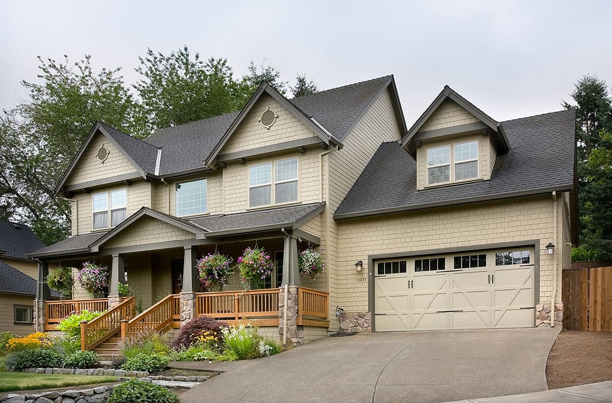 Two-story house plan exterior with covered porch, multiple gables, dormer, and a two-car side-entry garage.