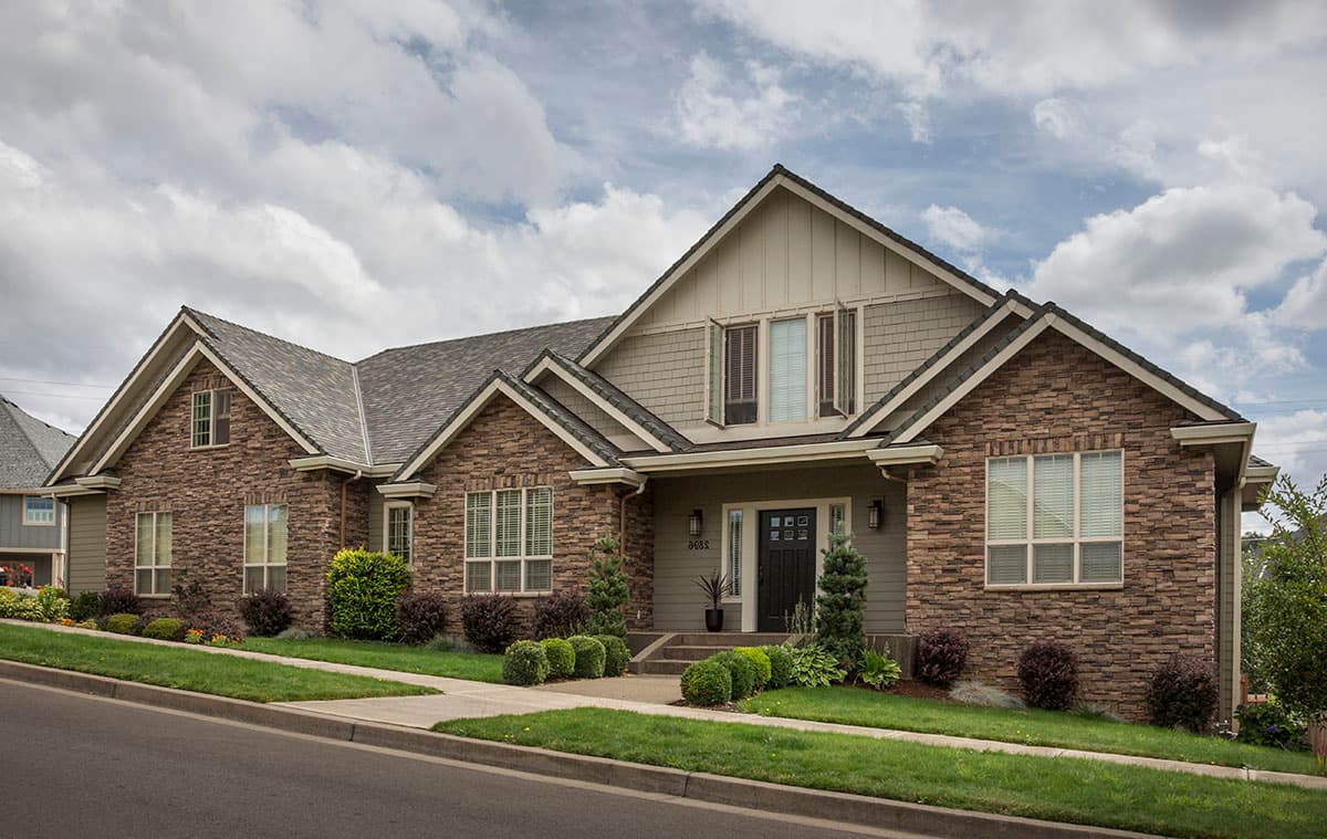 House plan exterior: Two-story home with stone veneer, gabled rooflines, dormers, and covered entryway.