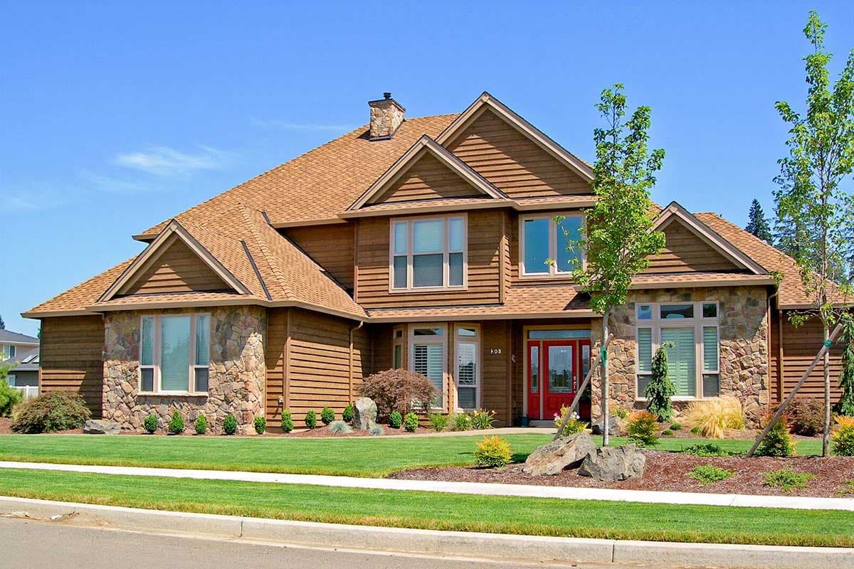 House plan exterior: two-story home with stone accents, horizontal siding, prominent gables, and a red front door.