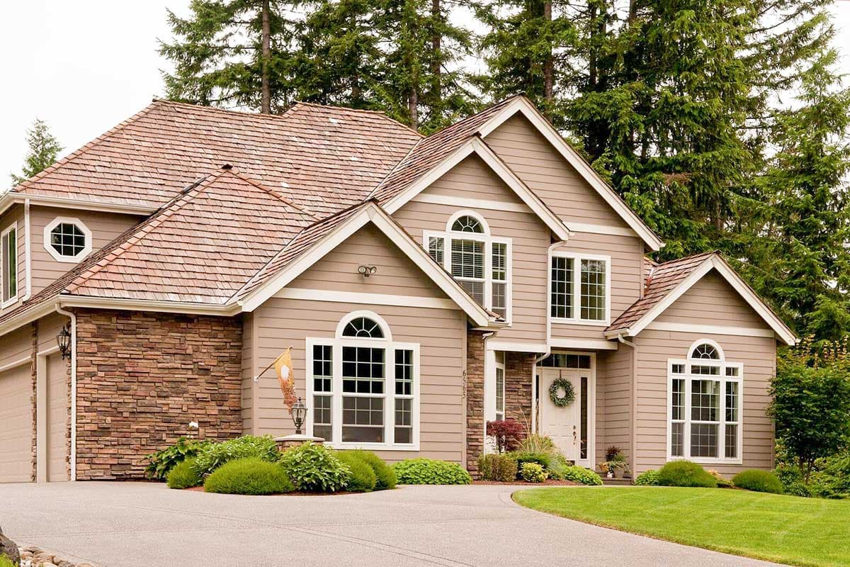 Two-story house plan exterior with a gable roof, arched windows, stone accents, and a two-car garage.