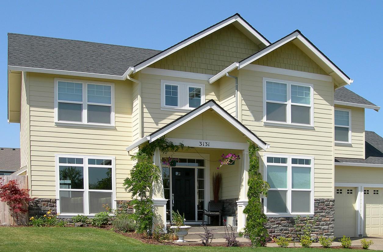 Two-story house plan exterior with siding, stone base, gabled entrance porch, multiple gables, and attached garage.