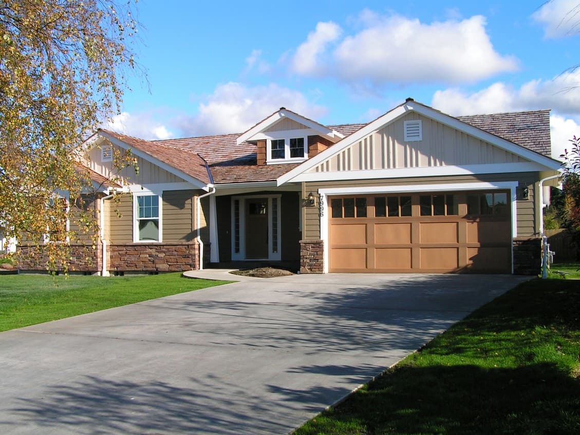 House plan exterior: Ranch style, 1 story, stone accents, wide front entrance, and attached garage with segmented door.