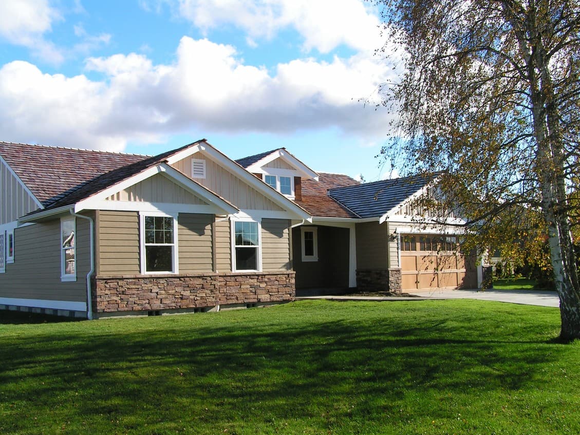 House plan exterior: one-story home with stone wainscoting, gabled dormers, and attached garage.