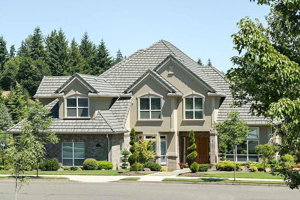 House plan exterior: Two-story home with gabled dormers, brick accents, and a covered entry.