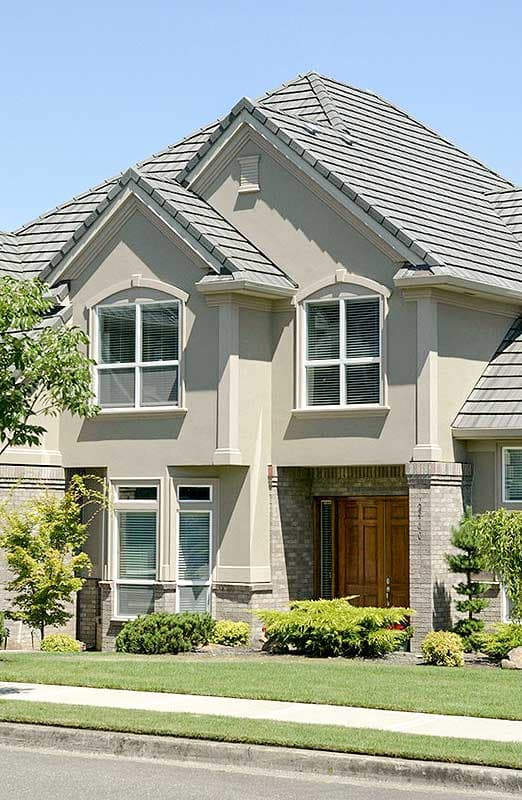 House plan exterior showing a two-story stucco home with gabled roof, arched windows, and brick accents around the entrance.
