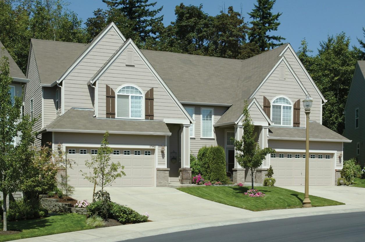 House plan exterior: Two-story home with a multi-level roof, arched windows with shutters, and a three-car garage.