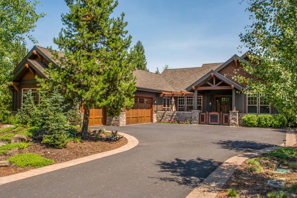 House plan exterior. Craftsman style with a gabled roof, timber-framed entry porch, and attached garage with wood doors.