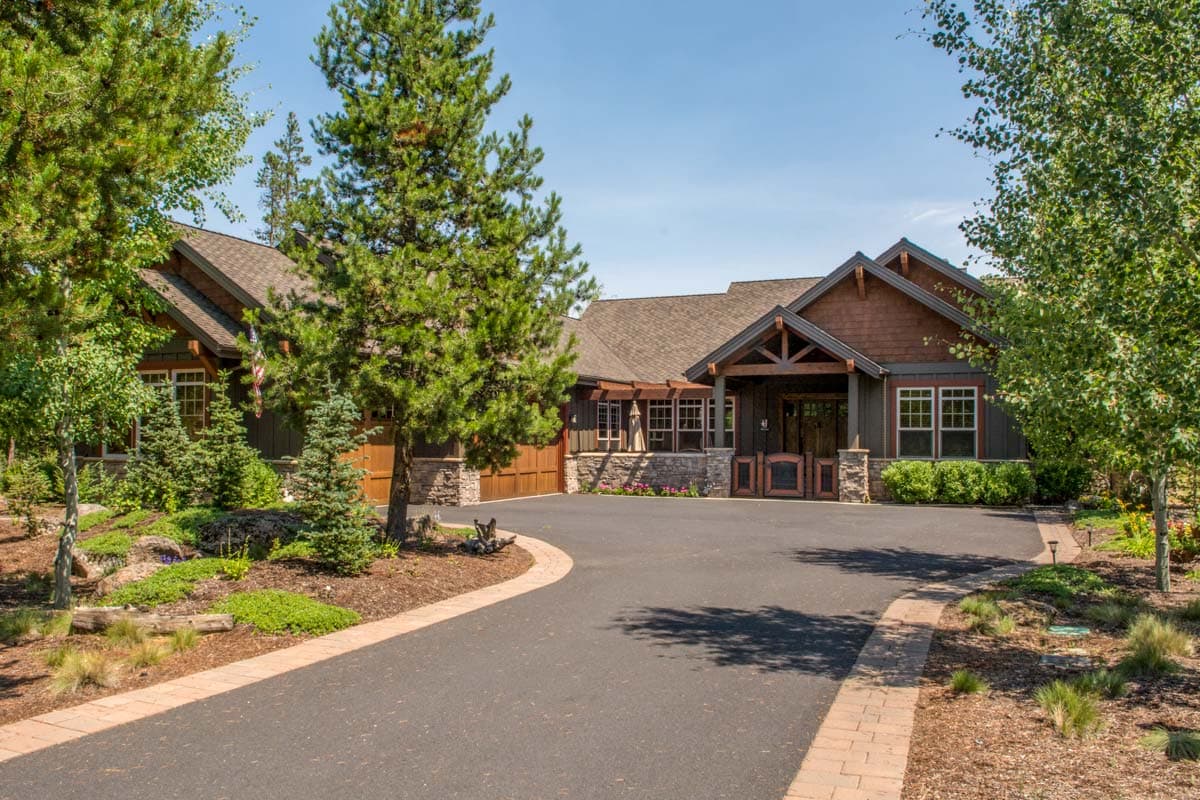 House plan exterior: Ranch-style home with covered entrance, exposed beams, stone accents, and a two-car garage.