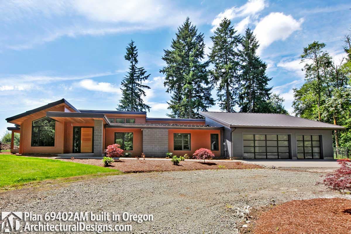 Modern house plan exterior with wood and concrete siding, asymmetrical rooflines, large windows, and a three-car garage.