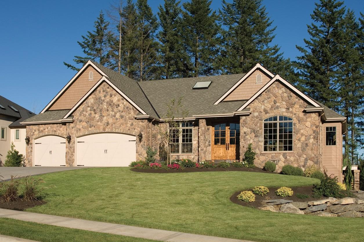 House plan exterior of a single-story home with a stone facade, arched double garage doors, gabled dormers, and a prominent arched window.