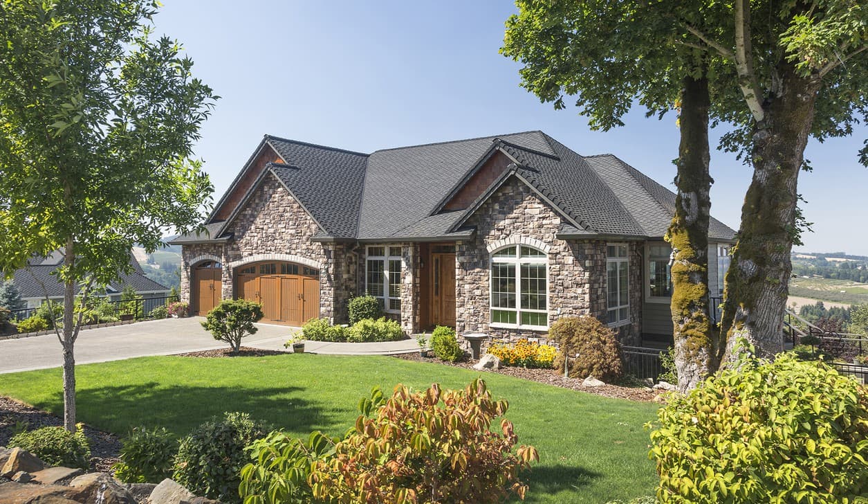 House plan exterior: Two-story Modern Farmhouse with stone facade, arched wood garage doors, and multiple gables.