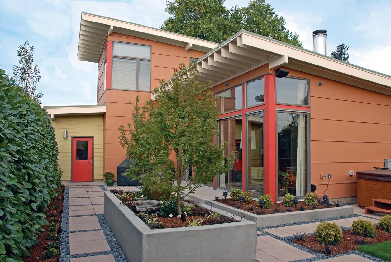 Modern house plan exterior with orange siding, cantilevered rooflines, and large glass windows.