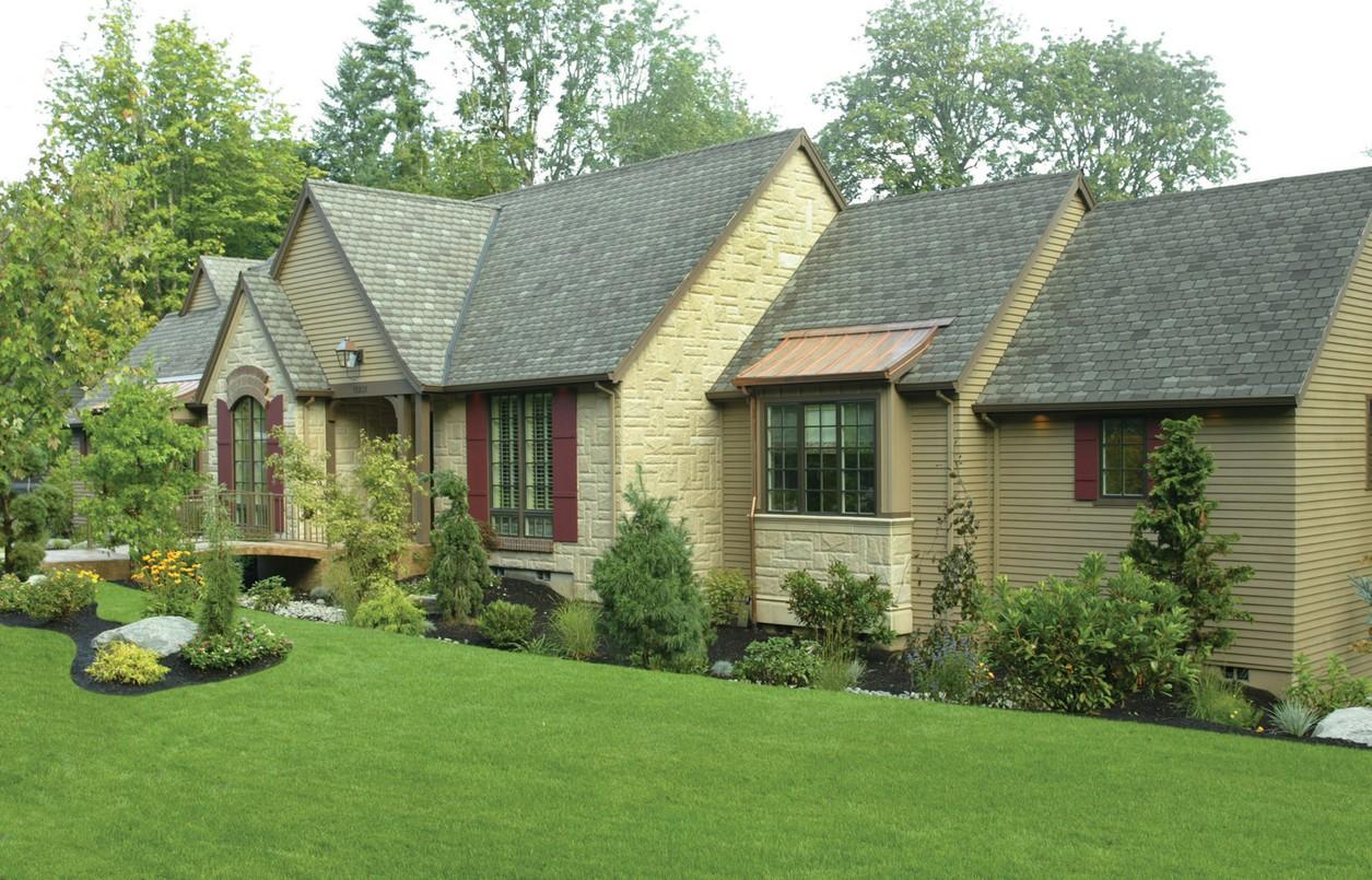 House plan exterior showing a two-story home with gables, stone accents, multiple dormers, and a copper bay window roof.