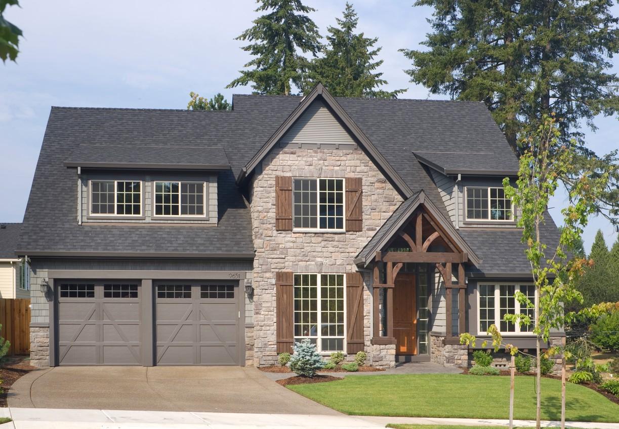 House plan exterior featuring a stone facade, double garage, multiple gables, and a prominent timber-framed entry porch.