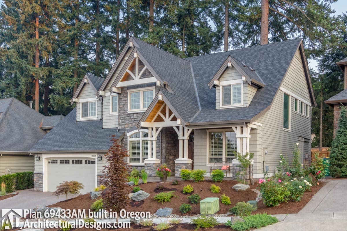 House plan exterior features a prominent covered entry with stone accents, gables, dormers, and a side-entry garage.