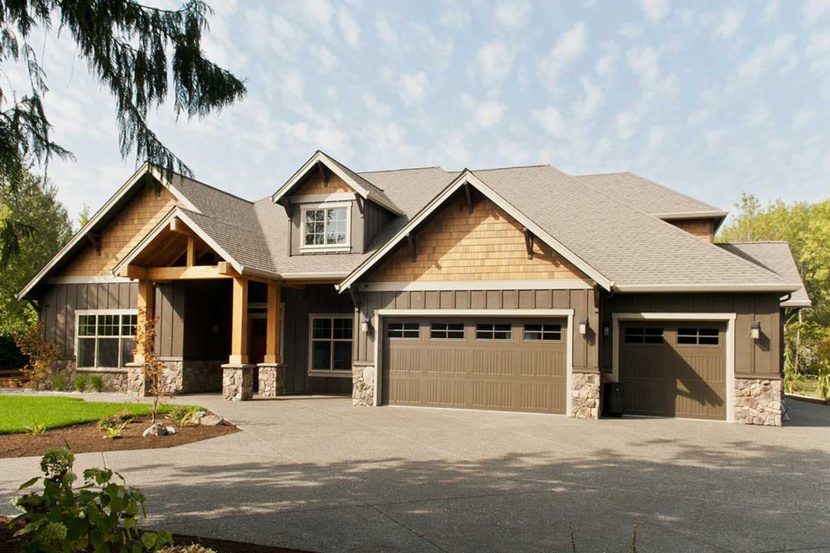 Craftsman house plan exterior with a covered entry, dormer, cedar shakes, stone accents, and a three-car garage.