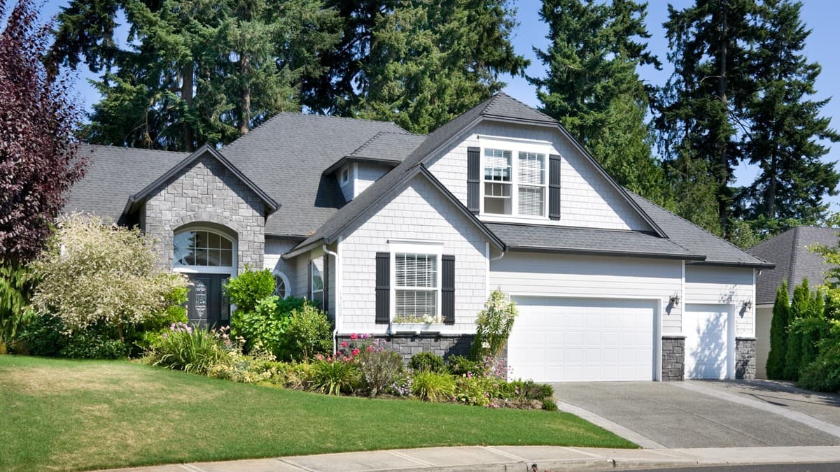 House plan exterior: Two-story home with stone accents, multi-gabled roof, dormer, and attached three-car garage.
