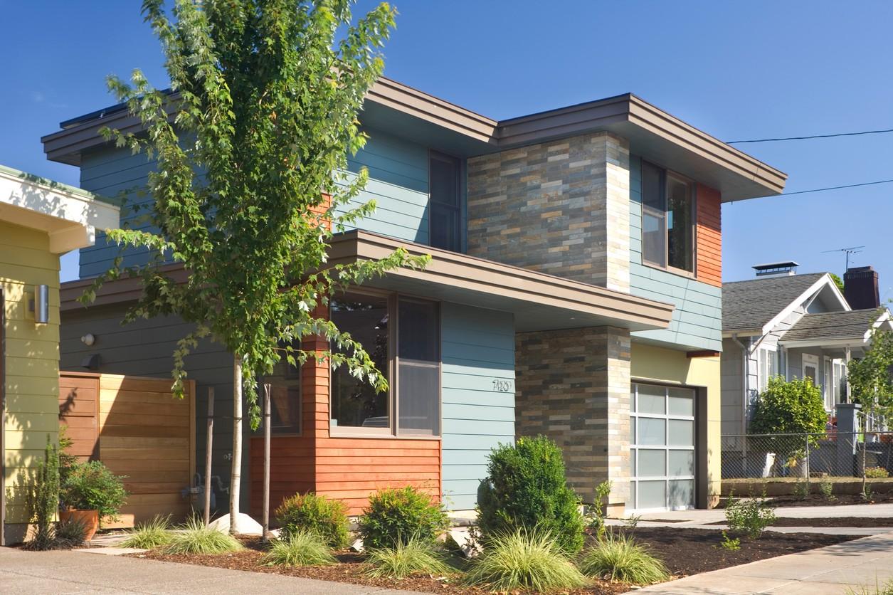 House plan exterior with two stories, horizontal siding, stone accents, and a modern garage door.