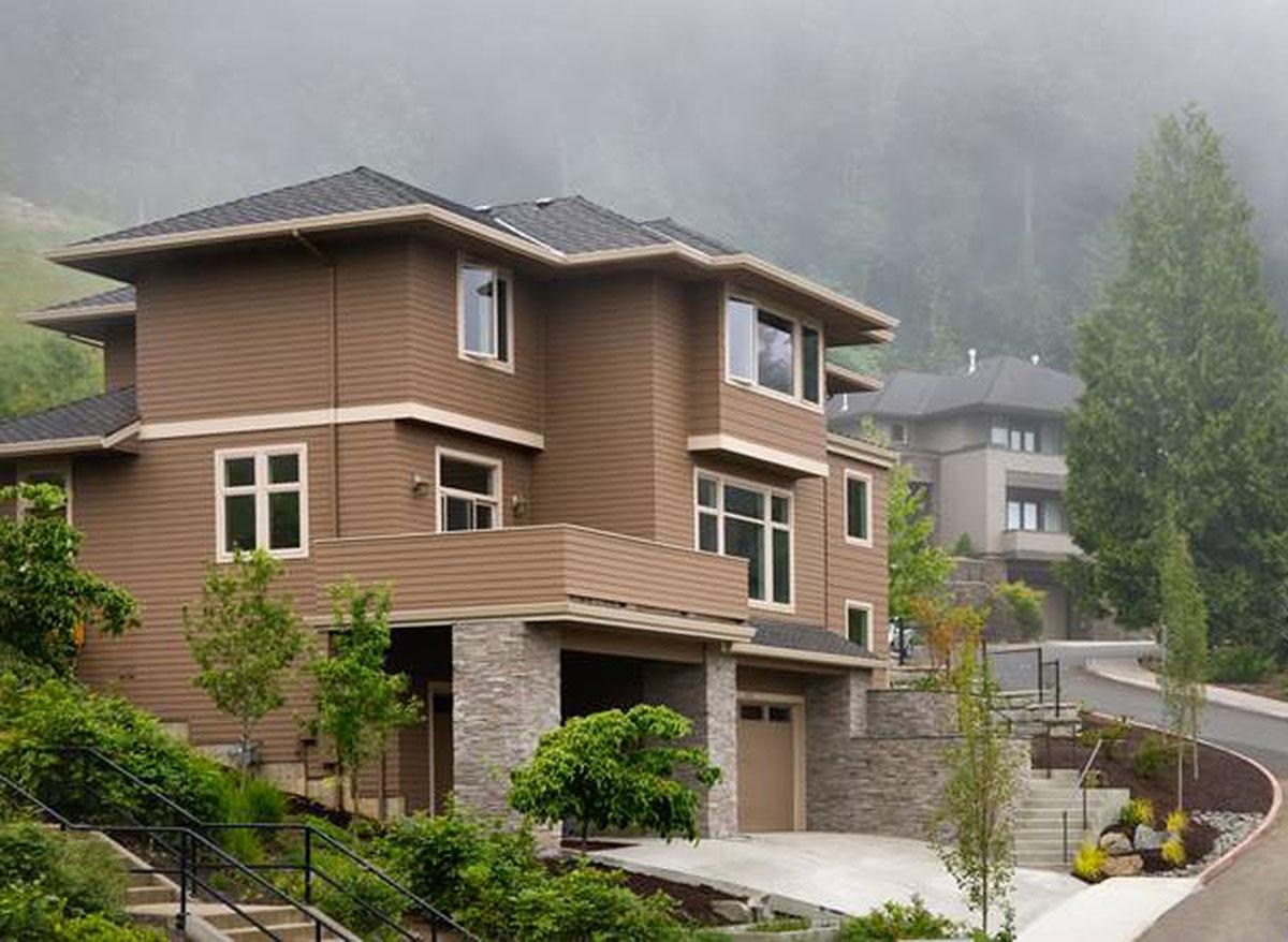 Modern house plan exterior with stacked stone foundation, covered balcony, and multi-level rooflines.