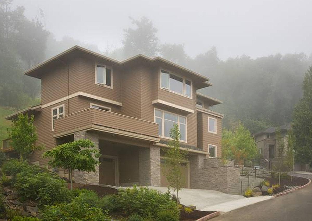 Modern house plan exterior with stacked stone accents, deep overhangs, and a lower-level garage.
